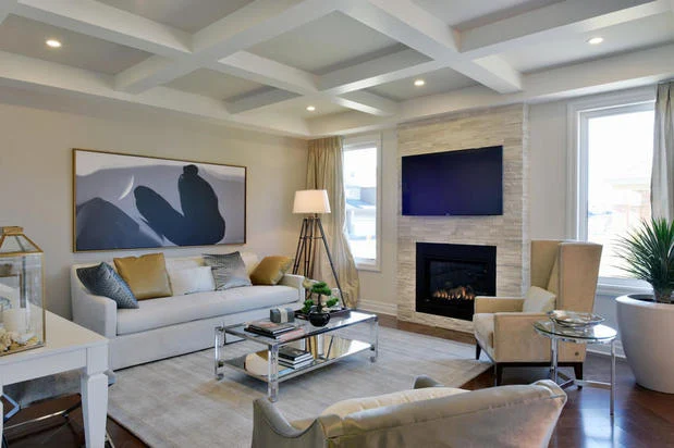 Minto Communities living room with coffered ceiling, stone fireplace, and elegant modern furnishings